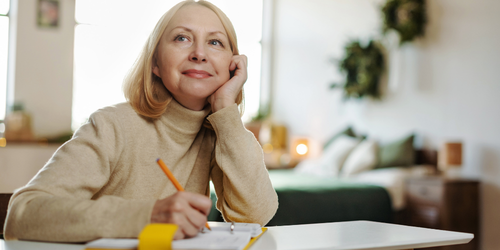 Femme adulte écrivant dans un carnet à son bureau. 