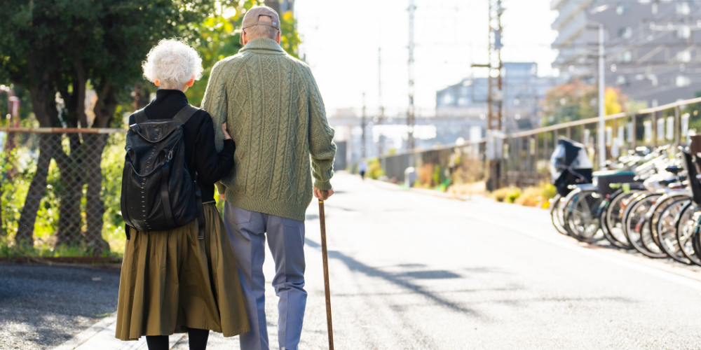 Older adult couple walking arm in arm.