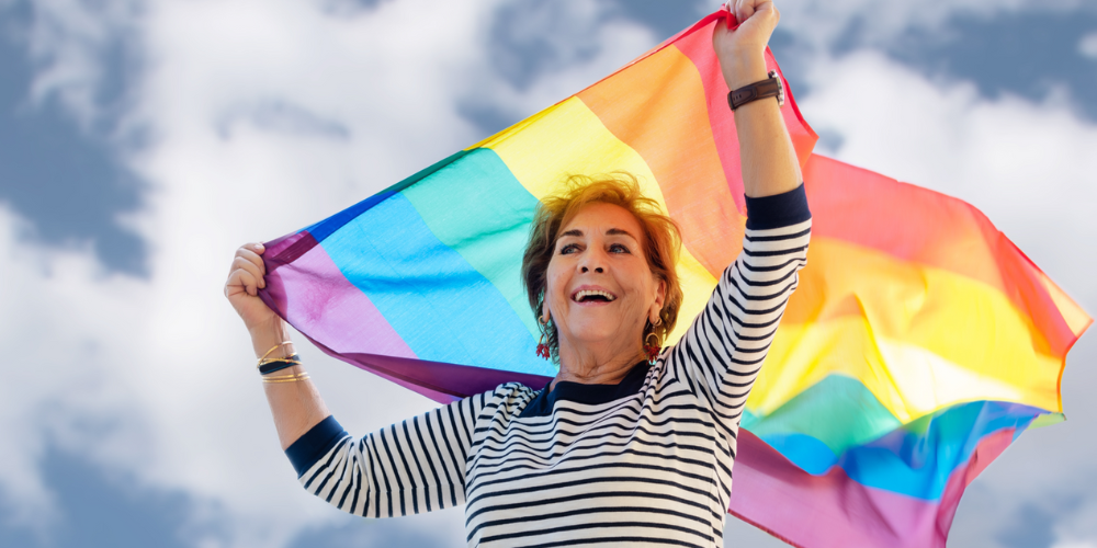 Adult woman holding a rainbow flag.