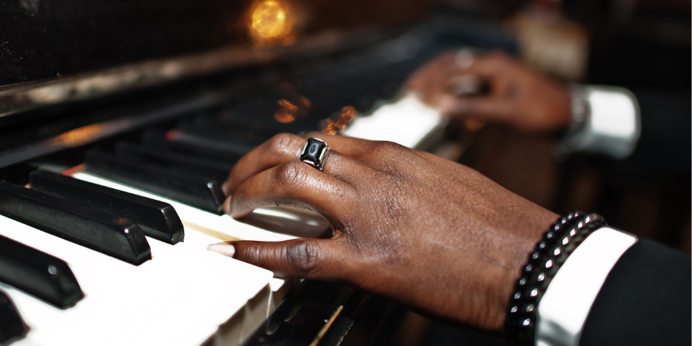 Gros plan de mains jouant du piano sur un fond sombre.