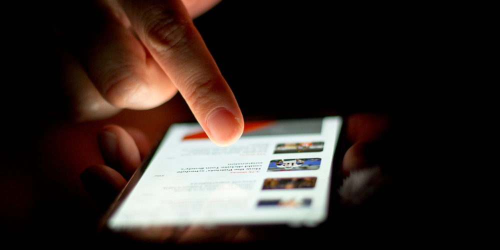 Gros plan de mains masculines utilisant un téléphone intelligent.