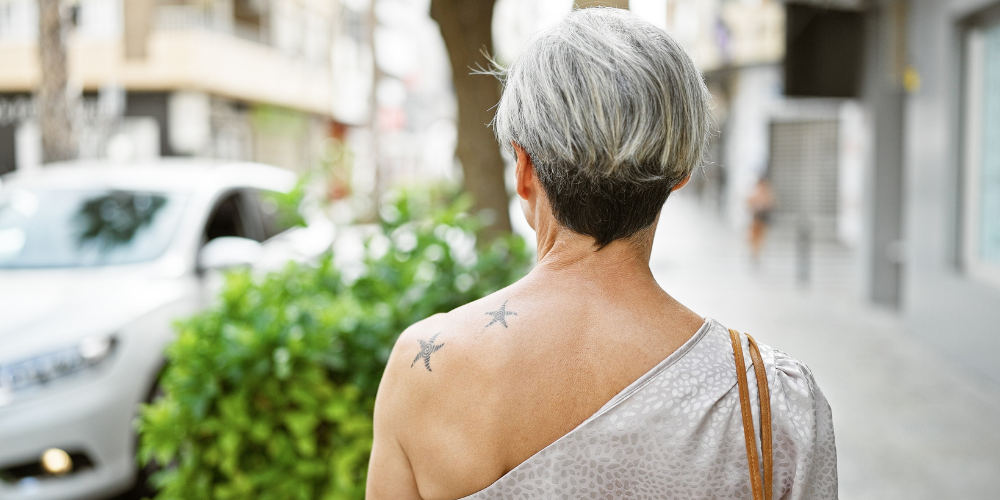 Femme tatouée aux cheveux courts, en train de marcher dans une rue urbaine.