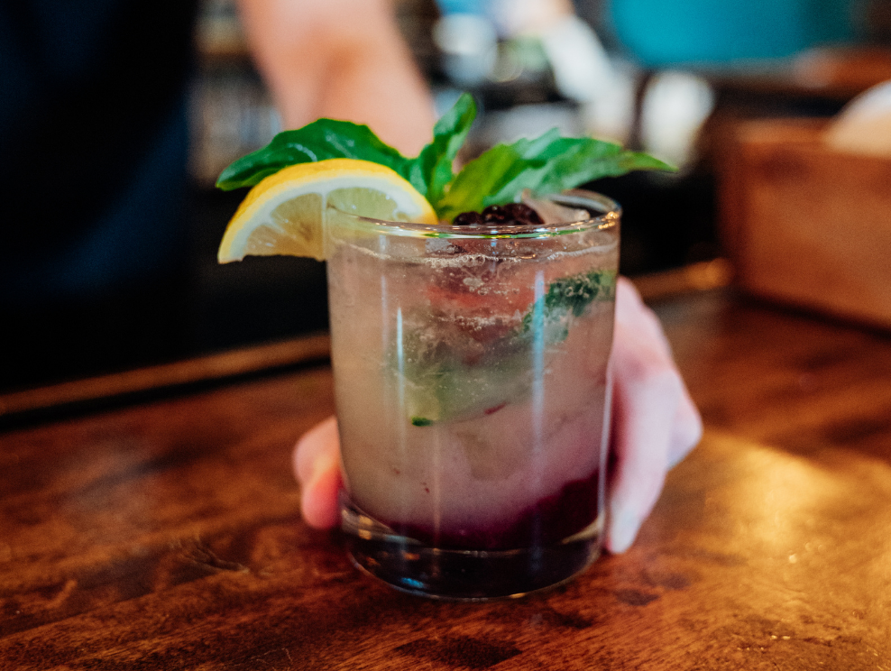 Bartender holding the Forager Smash cocktail.