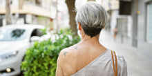 Femme tatouée aux cheveux courts, en train de marcher dans une rue urbaine.
